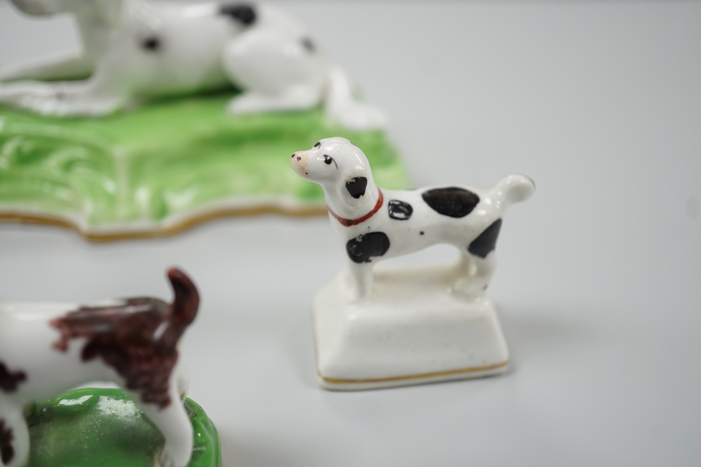 Three toy Staffordshire models of standing terriers; two with brown spots and the other black spots, together with a small Staffordshire model of a recumbent black and white setter on modelled base. c.1830-50, Largest 13